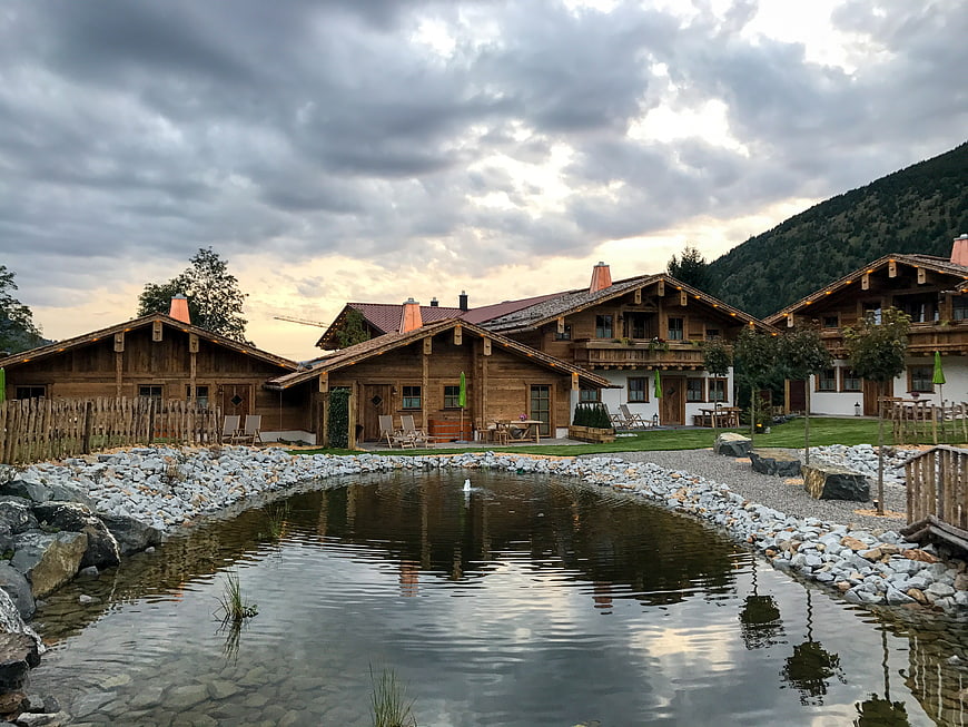 Traditional wooden chalets with pond and mountain backdrop