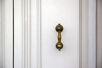 Close-up of vintage brass door handle on white paneled door