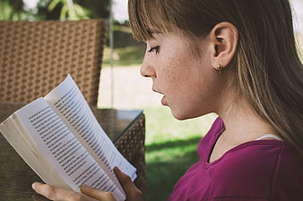 Girl Reading Book Outdoors in Profile