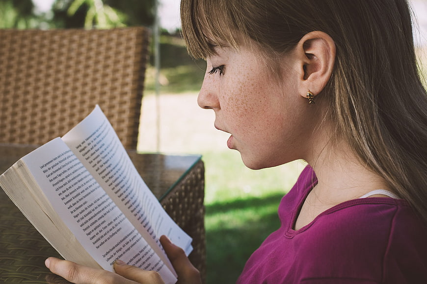 Girl Reading Book Outdoors in Profile
