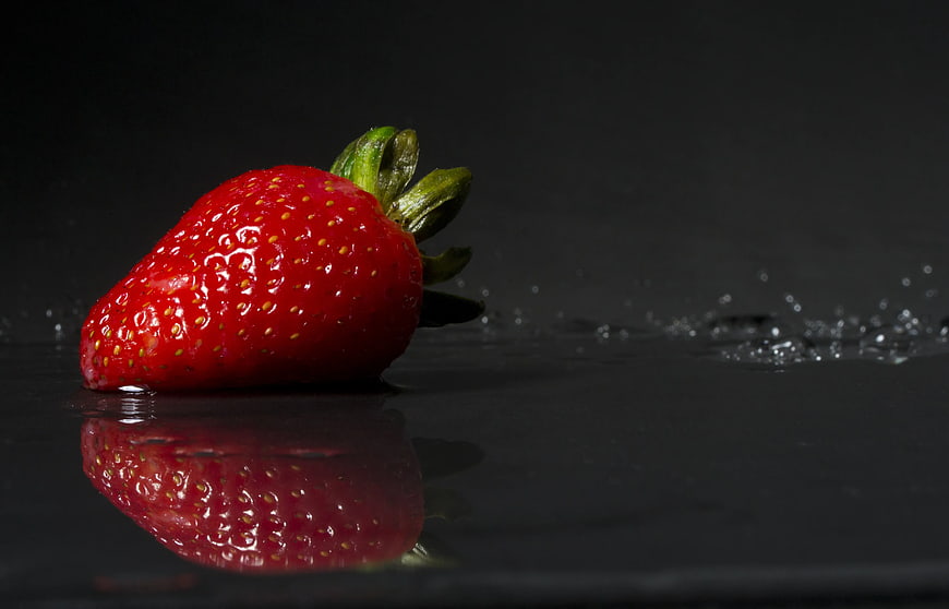 Fresh Red Strawberry on Black Surface with Water Splash