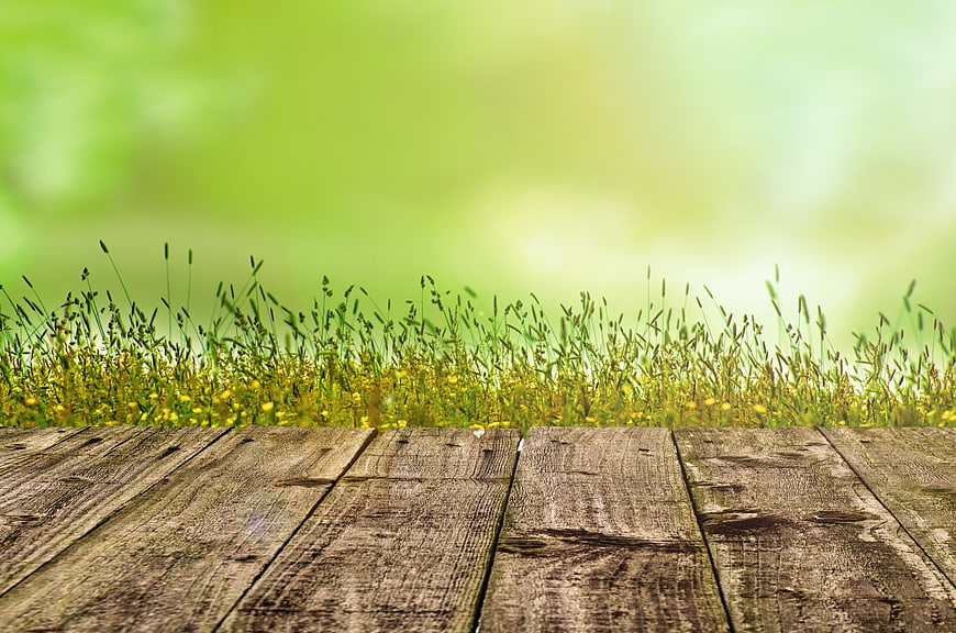 Rustic wooden table with blurred green meadow background