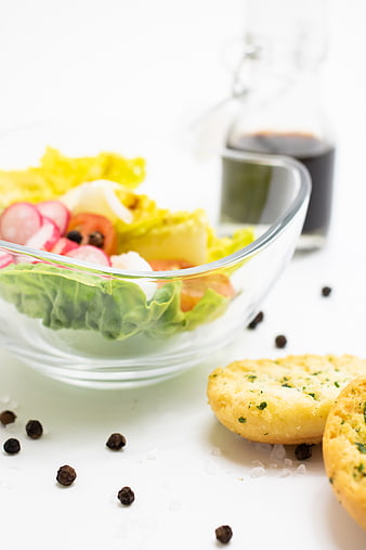 Fresh salad bowl with radishes and garlic bread on white background