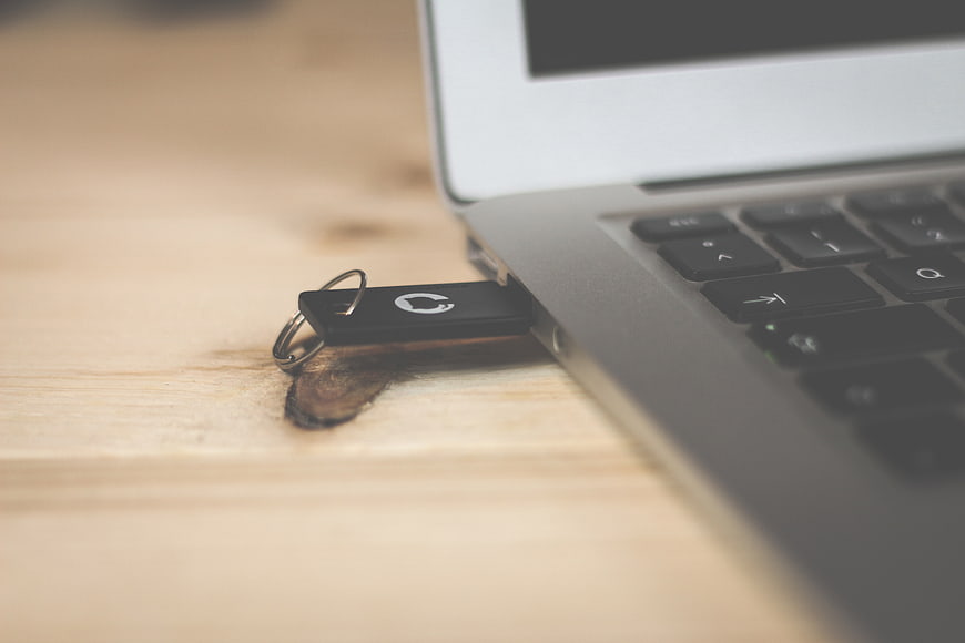 USB Flash Drive Plugged into Laptop on Wooden Desk