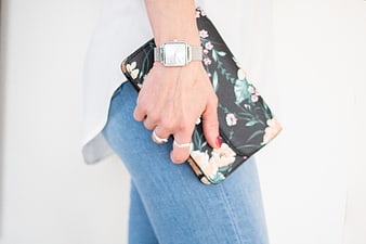 Woman holding floral clutch purse with silver watch