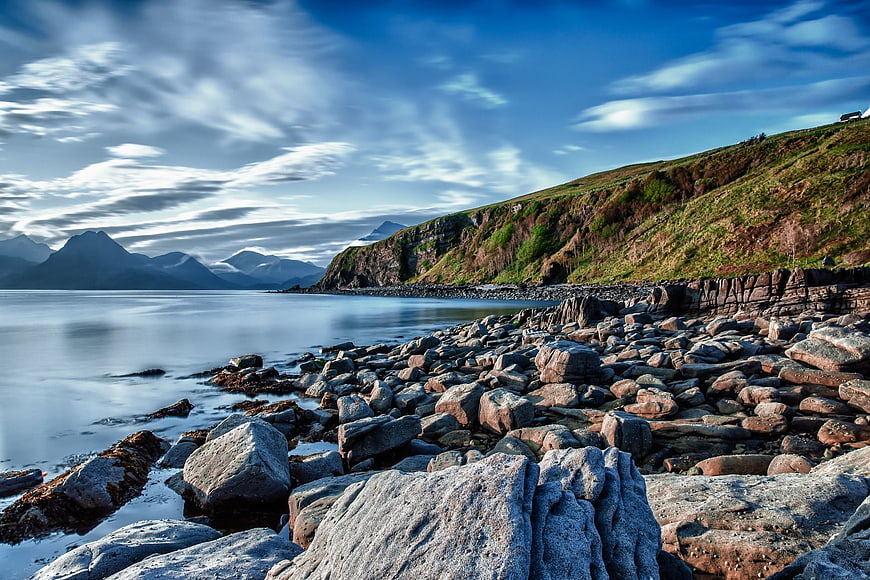 Scenic Rocky Coastline with Smooth Ocean and Distant Mountains