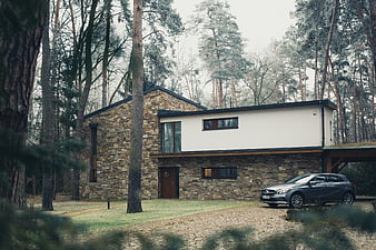 Modern stone house in pine forest with parked car