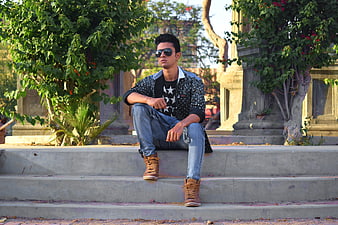 Stylish young man sitting on outdoor concrete steps