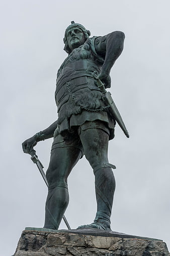 Low angle view of bronze warrior statue on stone pedestal