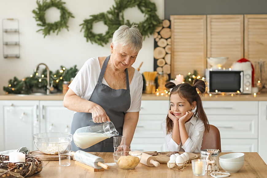 Grandmother and granddaughter baking cookies in a festive kitchen