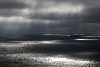 Dramatic Sunbeams Breaking Through Dark Storm Clouds Over Ocean