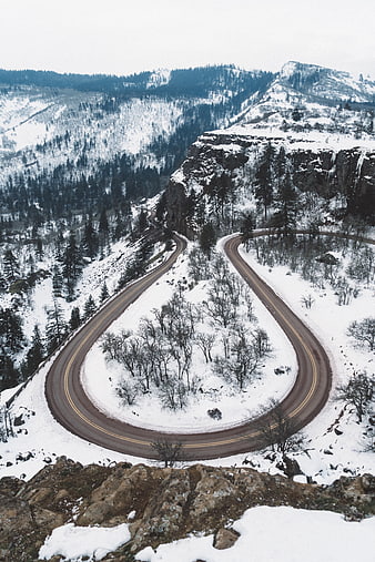 Winding mountain road with hairpin turn in snowy winter landscape