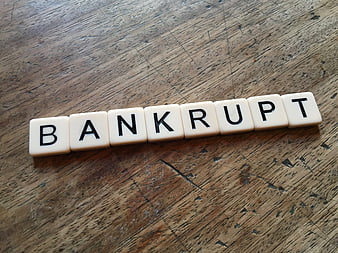 Scrabble tiles spelling bankrupt on rustic wooden table surface