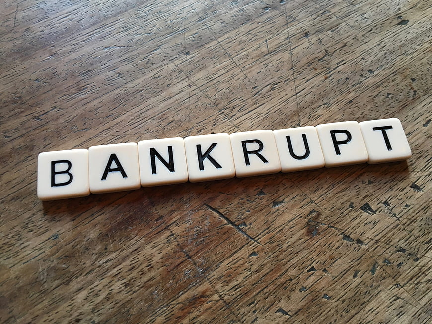 Scrabble tiles spelling bankrupt on rustic wooden table surface