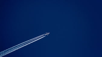 Airplane with Vapor Trails Against Deep Blue Sky