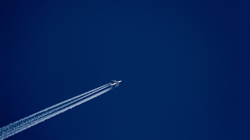 Airplane with Vapor Trails Against Deep Blue Sky
