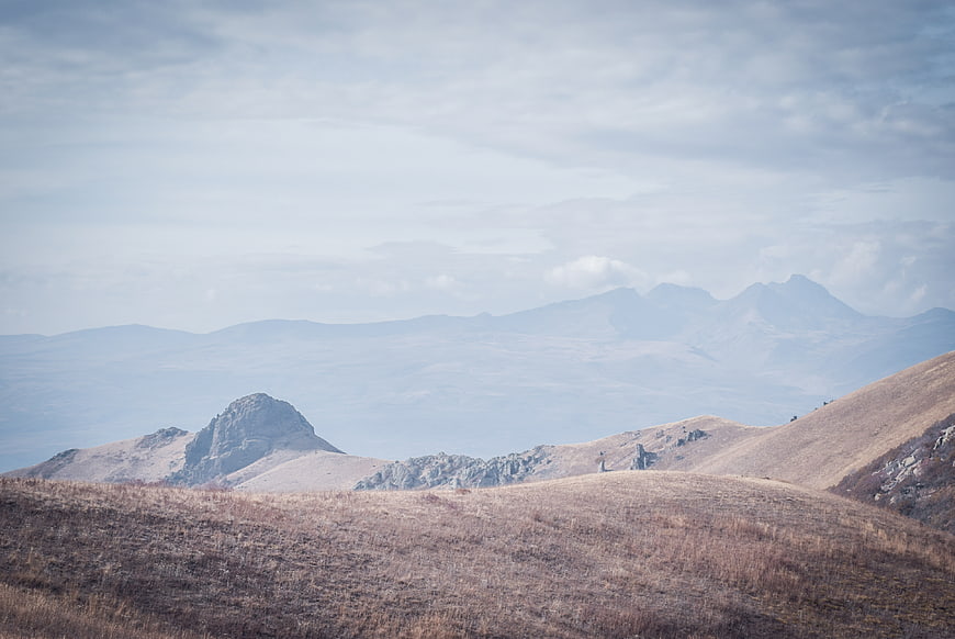 Serene mountain landscape with dry grassy hills and distant peaks