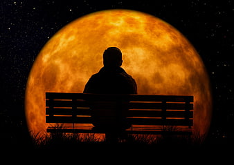 Silhouette of Man Sitting on Bench Before Giant Orange Moon