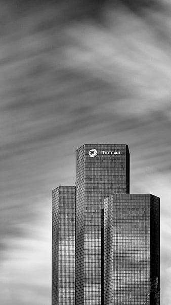 Black and white skyscraper with Total logo against cloudy sky