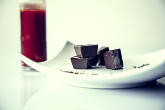 Dark chocolate squares on white plate with red juice