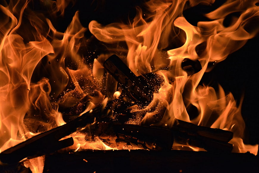 Close-up of burning wood logs with bright orange flames and sparks