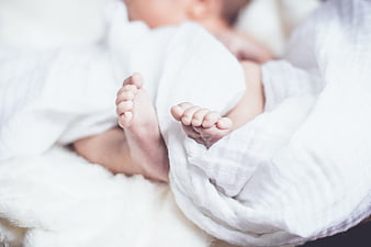 Close-up of newborn baby feet wrapped in white blanket