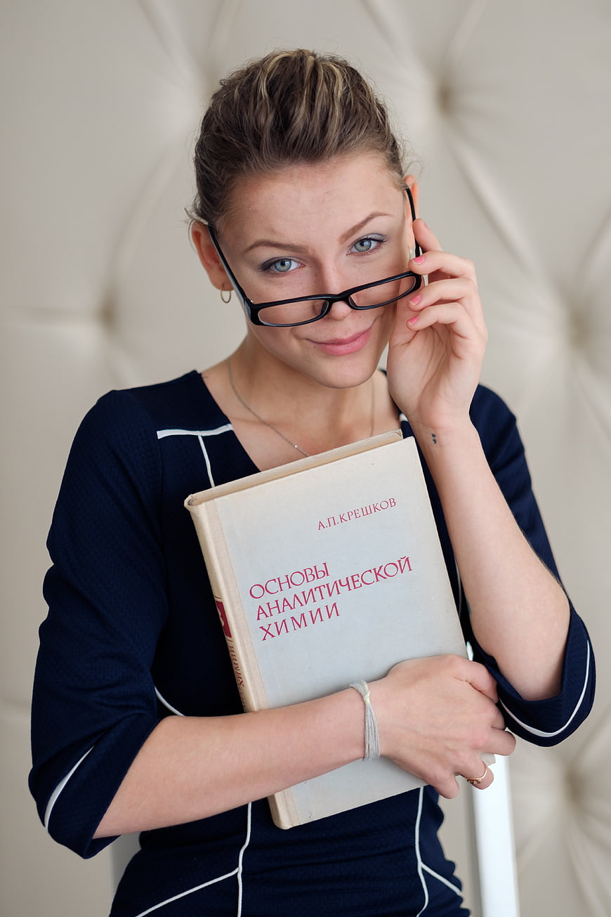 Young female student holding chemistry textbook and glasses