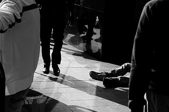 Black and white photo of homeless person lying on city sidewalk