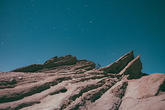 Lone hiker on rocky ridge under starry night sky