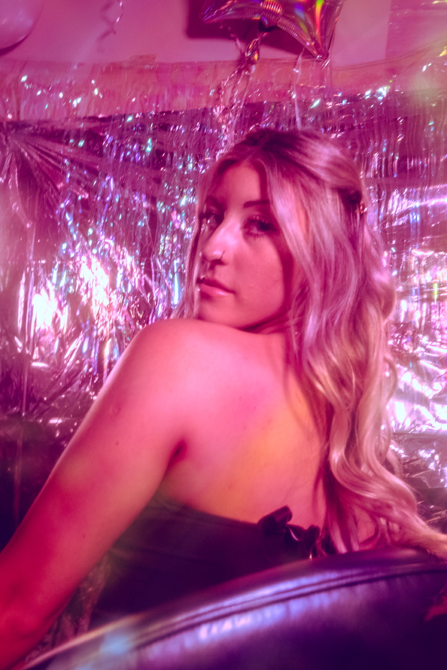 Blonde Woman in Pink Club Lighting with Tinsel Background