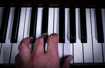 Close-up of hand playing piano keys