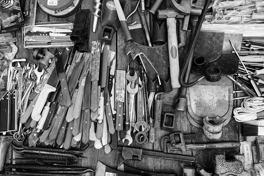 Black and white flat lay of assorted vintage tools and knives