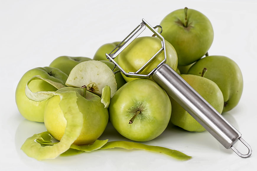 Green Apples with Silver Peeler on White Background