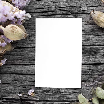 Blank white card on rustic wood with dried flowers