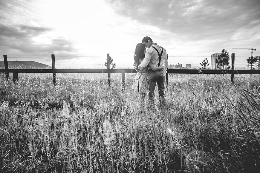 Romantic black and white couple kissing in tall grass field