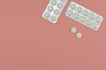 Silver blister packs and white pills on pink background