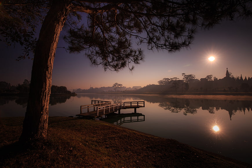 Serene Lake at Dawn with Wooden Pier and Distant Cathedral