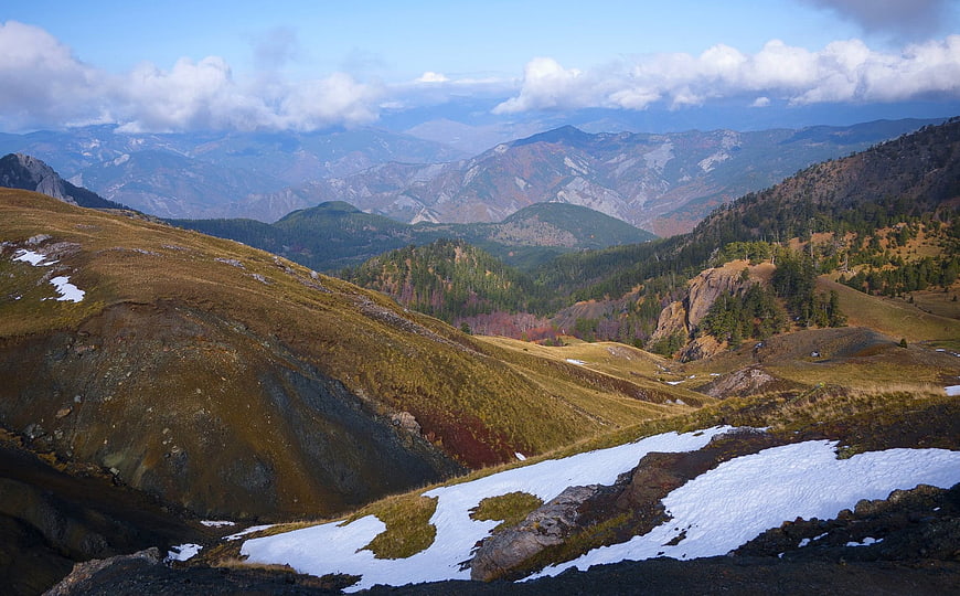 Autumn mountain landscape with snow patches and distant peaks