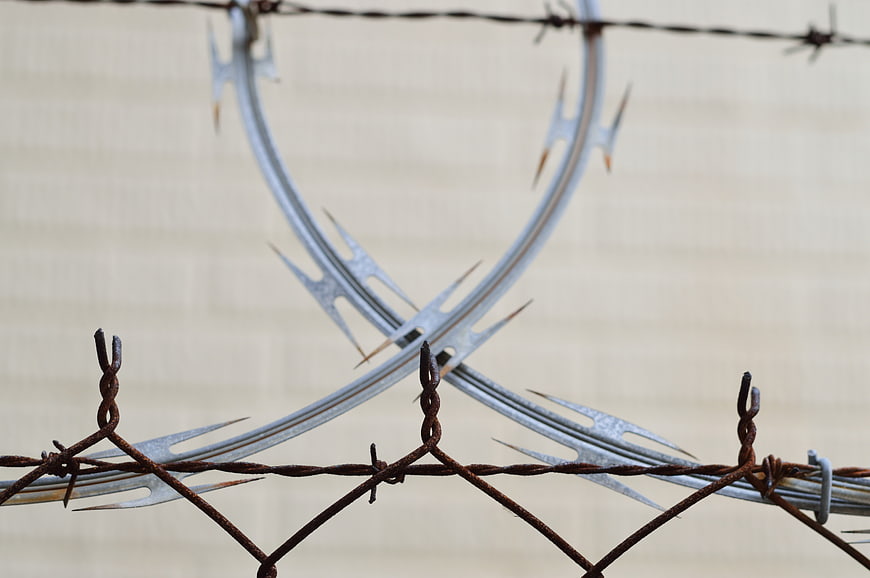 Close-up of rusty barbed wire and razor wire security fence