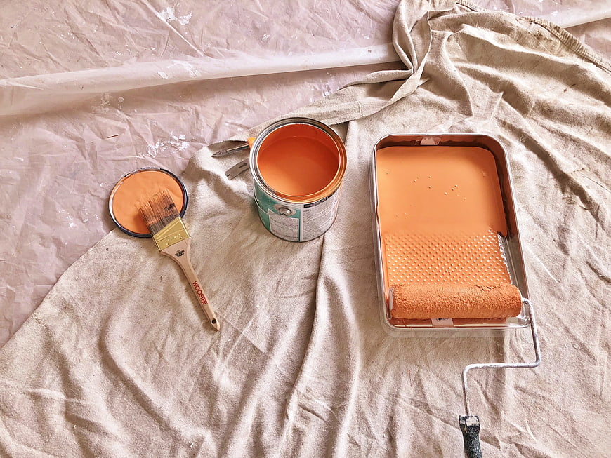 Orange Paint Can, Brush, and Roller on Drop Cloth