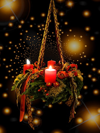 Advent wreath with lit red candles and festive decorations on dark background