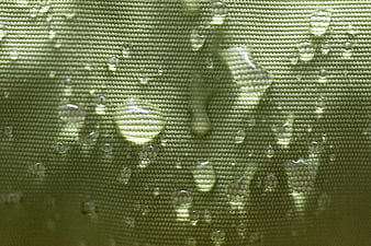 Macro shot of water droplets on green waterproof fabric texture