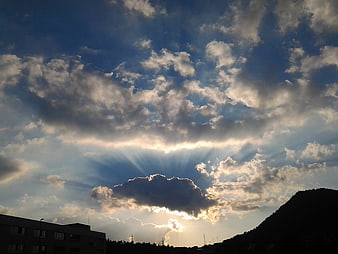 Dramatic Sun Rays Breaking Through Clouds Over Silhouette