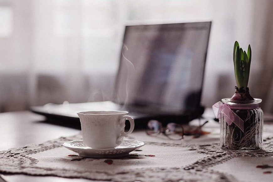 Steaming Coffee Cup and Laptop on Lace Tablecloth