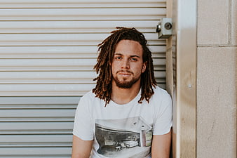 Portrait of man with dreadlocks leaning against wall