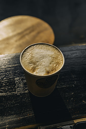 Top View of Foamy Coffee in Paper Cup on Dark Wood
