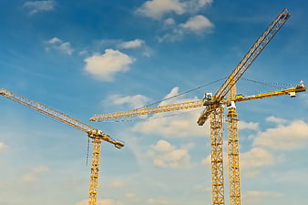 Yellow Construction Cranes Against Blue Sky With Clouds