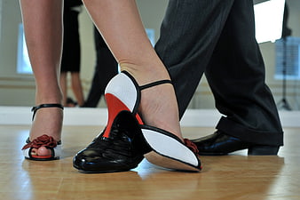 Close-up of tango dancers' feet on wooden floor