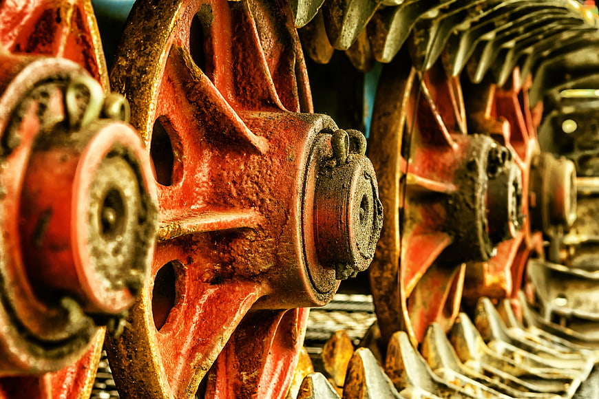 Close-up of rusty red tractor wheels and chain drive mechanism