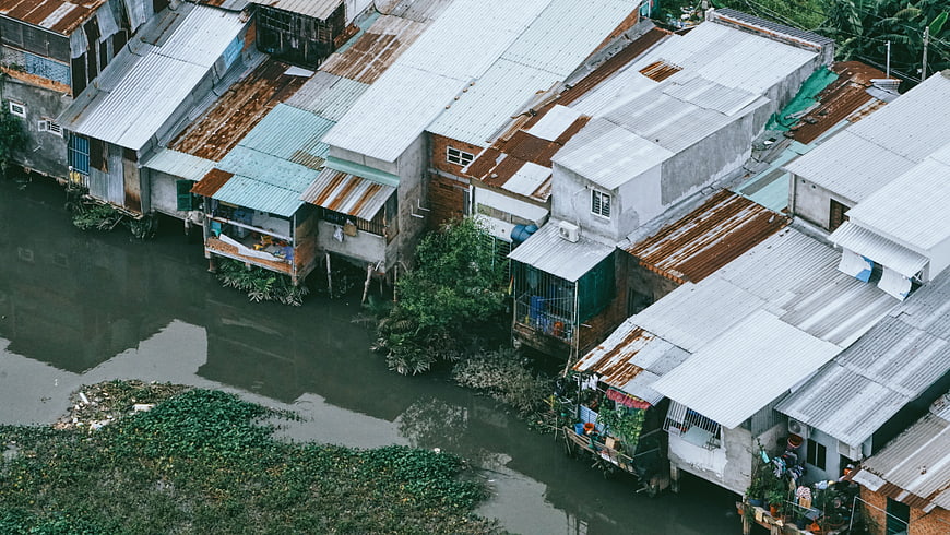 Aerial view of stilt houses along a river with rusty rooftops